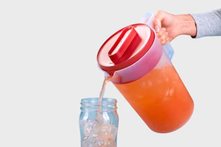 A beverage being poured into a glass cup from the Rubbermaid 1-gallon pitcher