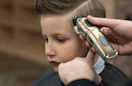 a person cutting a kid's hair with hair clippers