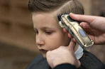 a person cutting a kid's hair with hair clippers