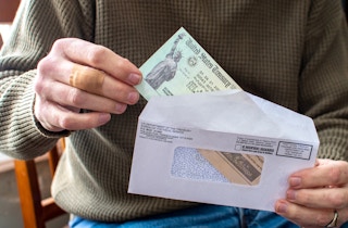 A person taking a check from the US Treasury out of an envelope