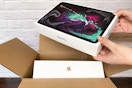 A person taking an iPad pro out of a shipping box with another Apple product inside.