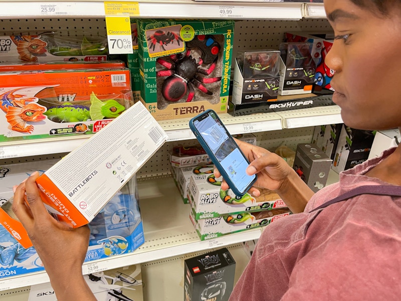 A person standing in the toy aisle at Target, scanning a clearance toy's barcode with the Target app.