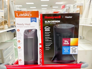 A Lasko and Honeywell heater sitting on a shopping cart.