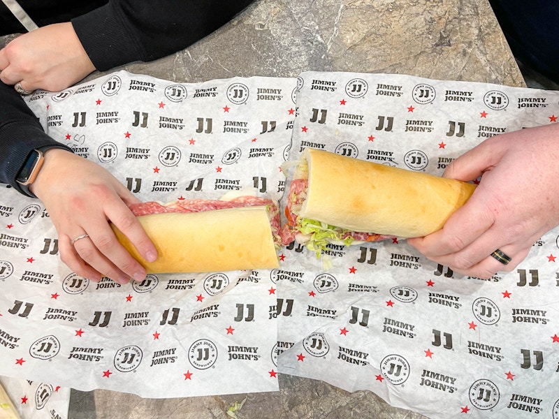 two hands holding cut giant sandwich