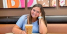 a person smiling with coffee inside of dunkin