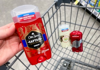 hand holding a stick of old spice deodorant and a walgreens shopping cart