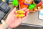 person holding 2 carmex lip balms by the checkout counter