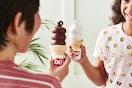 Two people. holding Dairy Queen cones, one regular and one dipped