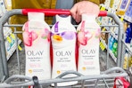 person pushing a cart with 3 bottles of olay body wash in it