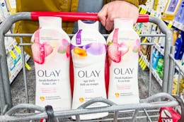 person pushing a cart with 3 bottles of olay body wash in it