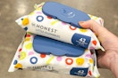 person holding 2 packs of honest wipes