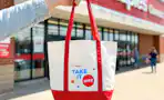 hand holding a staples tote bag in front of a staples store
