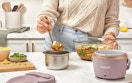 a person putting food in an electric lunch box on a kitchen counter