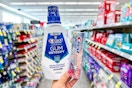 person holding crest mouthwash and toothpaste in an aisle