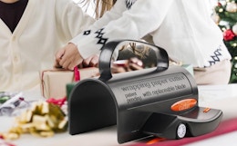 a couple wrapping a present next to a wrapping paper cutter