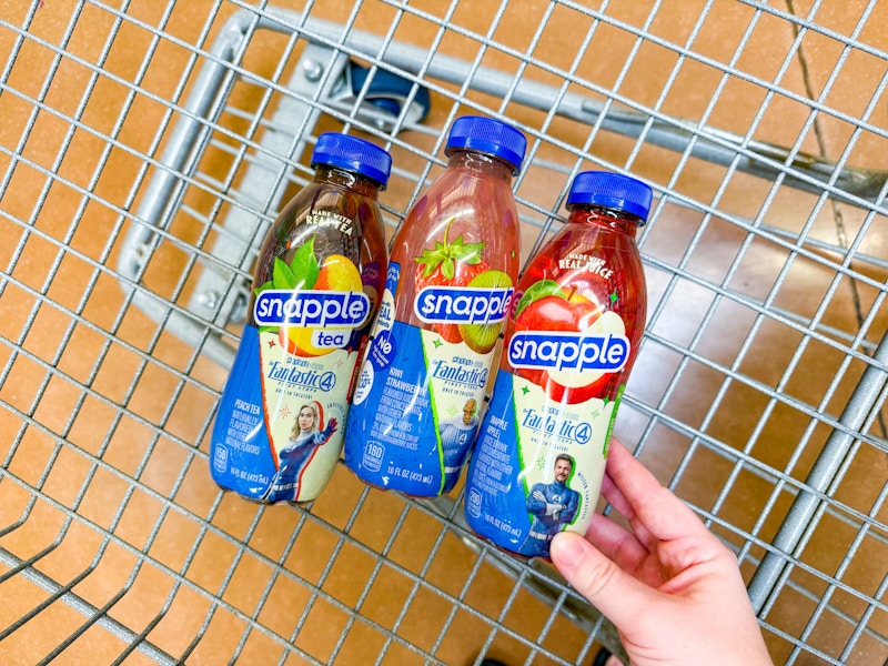 hand holding a bottle of snapple fantastic 4 drink with two more in walmart cart
