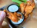 A dry rub seasoned traditional buffalo wings being dipped into ranch dressing.