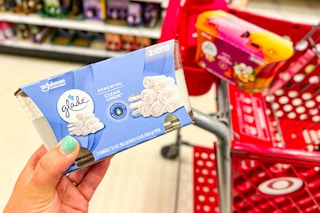 hand holding a twin pack of glade candles in front of target cart