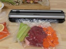 a vacuum sealer on a table sealing vegetables in a bag