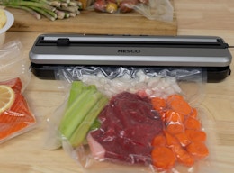 a vacuum sealer on a table sealing vegetables in a bag