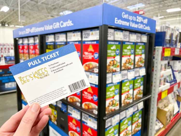 Hand holding a ticket for gift cards in front of gift card display at Sam's Club