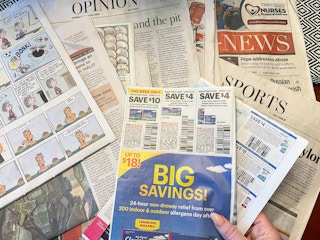 a person pulling coupon inset out of newspaper