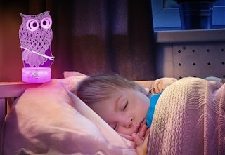 sleeping child in bed with owl night light lamp above head