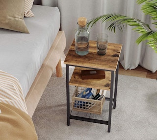 A three-tier end table next to a bed.