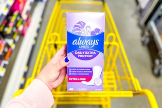 hand holding always liners above a yellow shopping cart