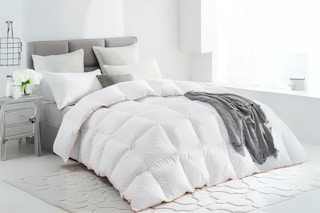 A down and feather blend comforter on a bed in a basic white room