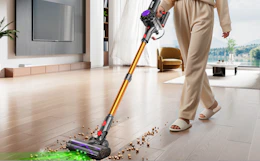 a person vacuuming crumbs off of a hardwood floor