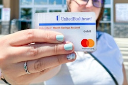 Someone holding up their HSA card outside of a store