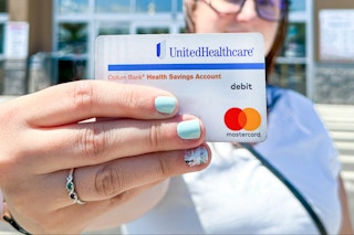 Someone holding up their HSA card outside of a store