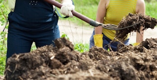two people shoveling mulch