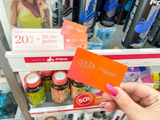 a person holding a credit card in store in front of rewards signage 