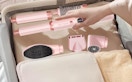 a hand putting a pink air hair styler in a suitcase