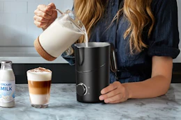 a woman pouring milk into a frother