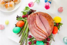 An Easter ham from FKroger sliced on a plate next to some colorful eggs