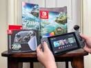 Someone holding a switch next to a Legend of Zelda Tears of the Kingdom game and limited edition switch console and pro controller