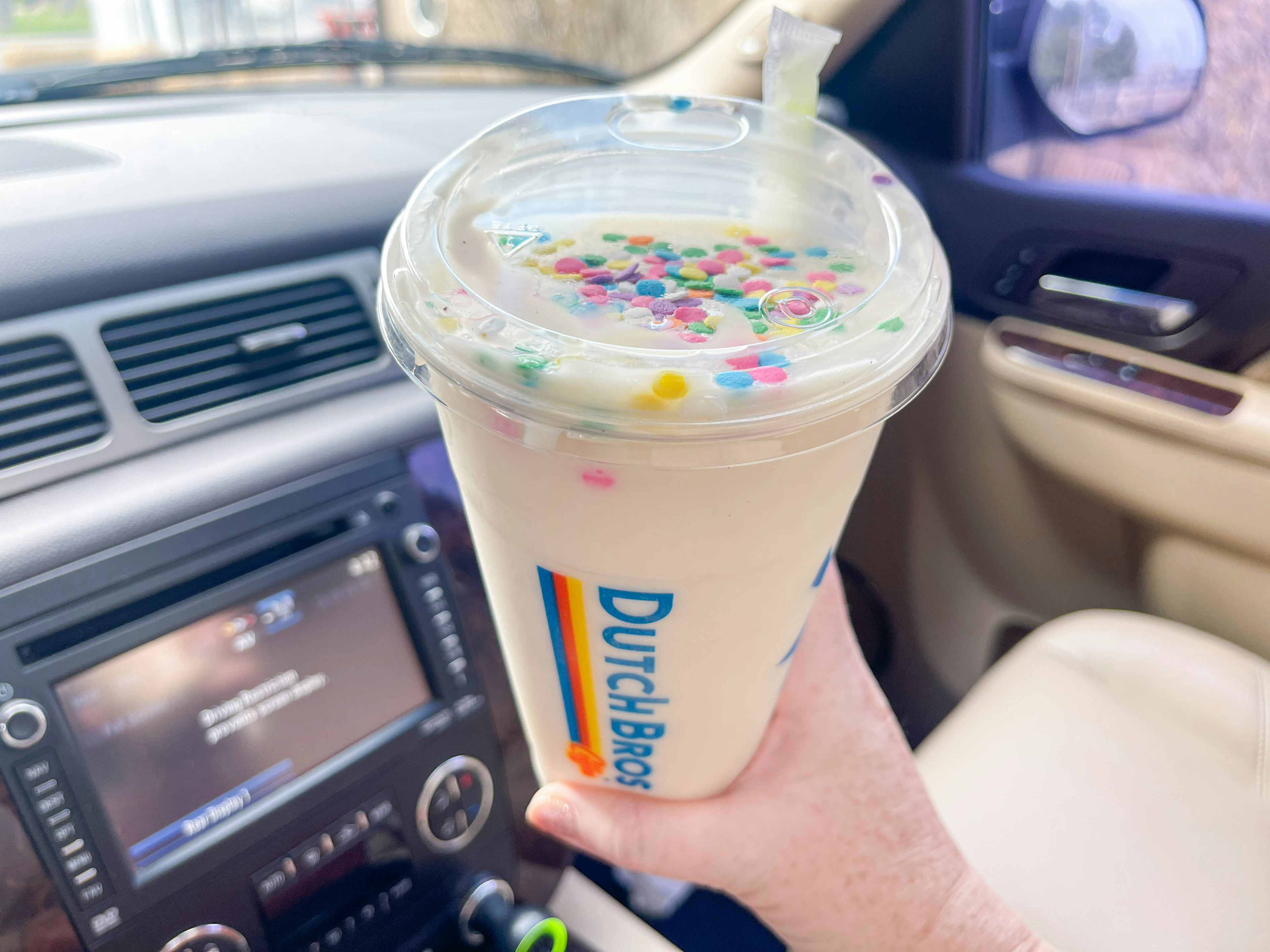 dutch bros birthday cake drink being held in a car 