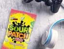 a pack of Sour Patch Kids next to a pair of headphones