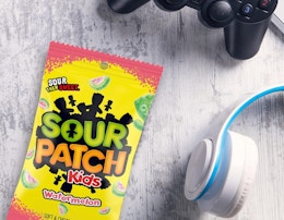 a pack of Sour Patch Kids next to a pair of headphones