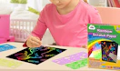 a kid drawing on rainbow scratch paper