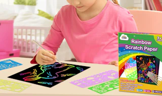 a kid drawing on rainbow scratch paper