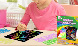a kid drawing on rainbow scratch paper
