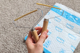 A hand holding portable lint removers over a delivery package.