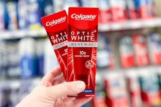 a hand holding two red boxes of toothpaste