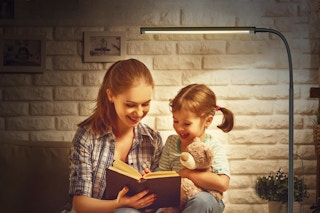 Woman reading to her child under LED floor lamp 