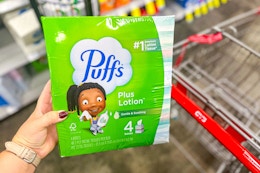 person holding a package of puffs tissues over a cart