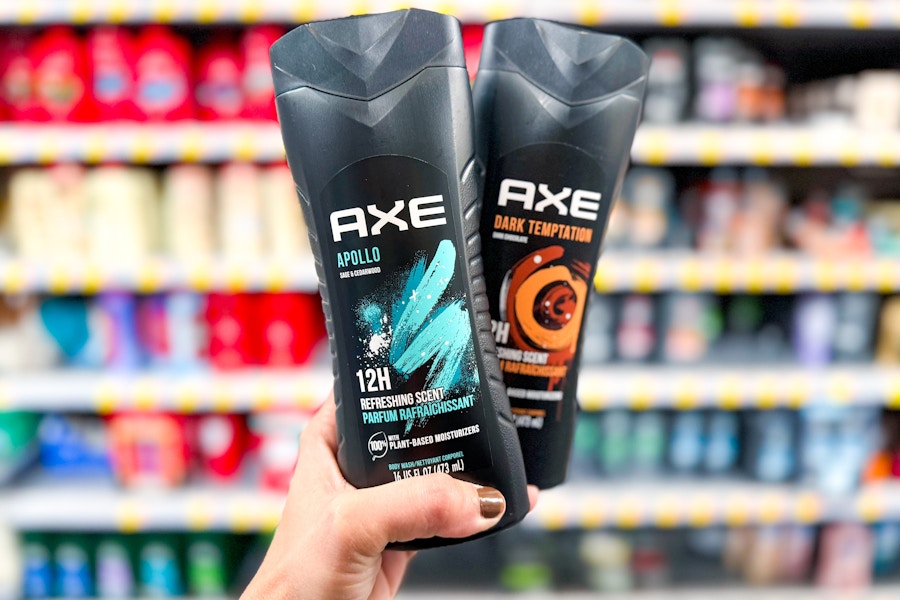 person holding 2 bottles of axe body wash in front of shelves